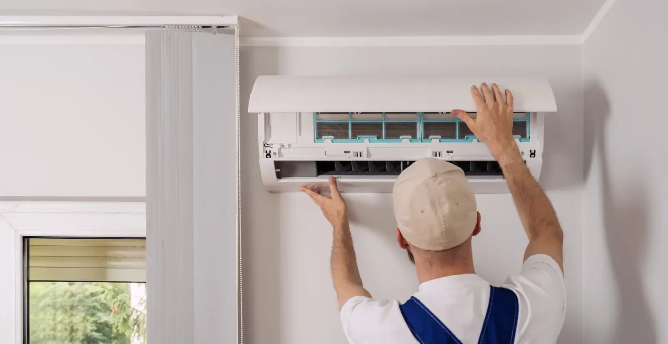 Technicien professionnel installant une unité de climatiseur split murale dans un salon résidentiel français