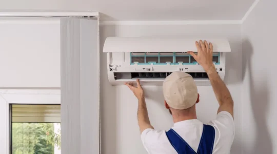 Technicien professionnel installant une unité de climatiseur split murale dans un salon résidentiel français
